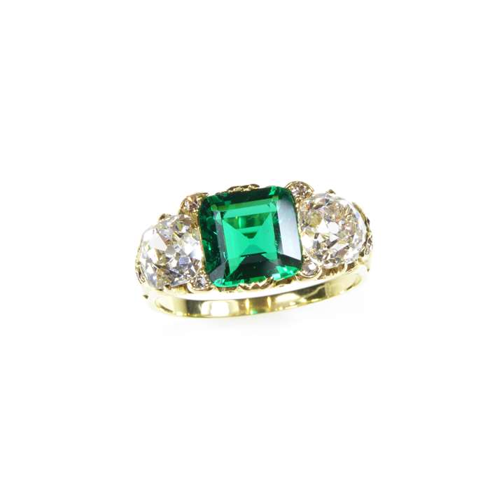 Emerald and diamond three stone ring centred by a square cut Colombian emerald